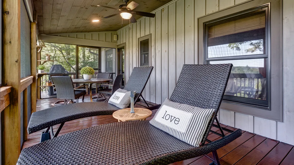 A serene nook with plush lounge chairs, decorative pillows, and a small side table, set in front of large windows that capture sunset hues. The setup provides an intimate spot for reading, relaxing, or enjoying drinks with friends while basking in the natural beauty outside.