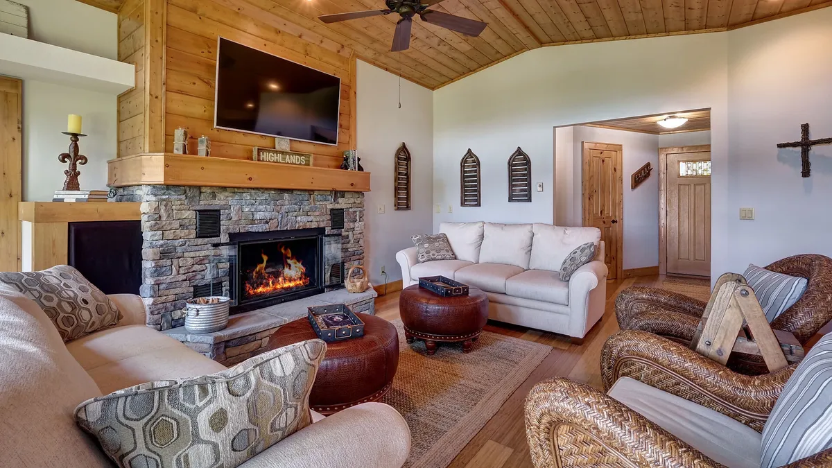 A warm and welcoming living space with a prominent stone fireplace, a cushy sofa, a wooden ceiling, and a coffee table perfect for board games or drinks. The arrangement encourages togetherness and shared moments with loved ones.